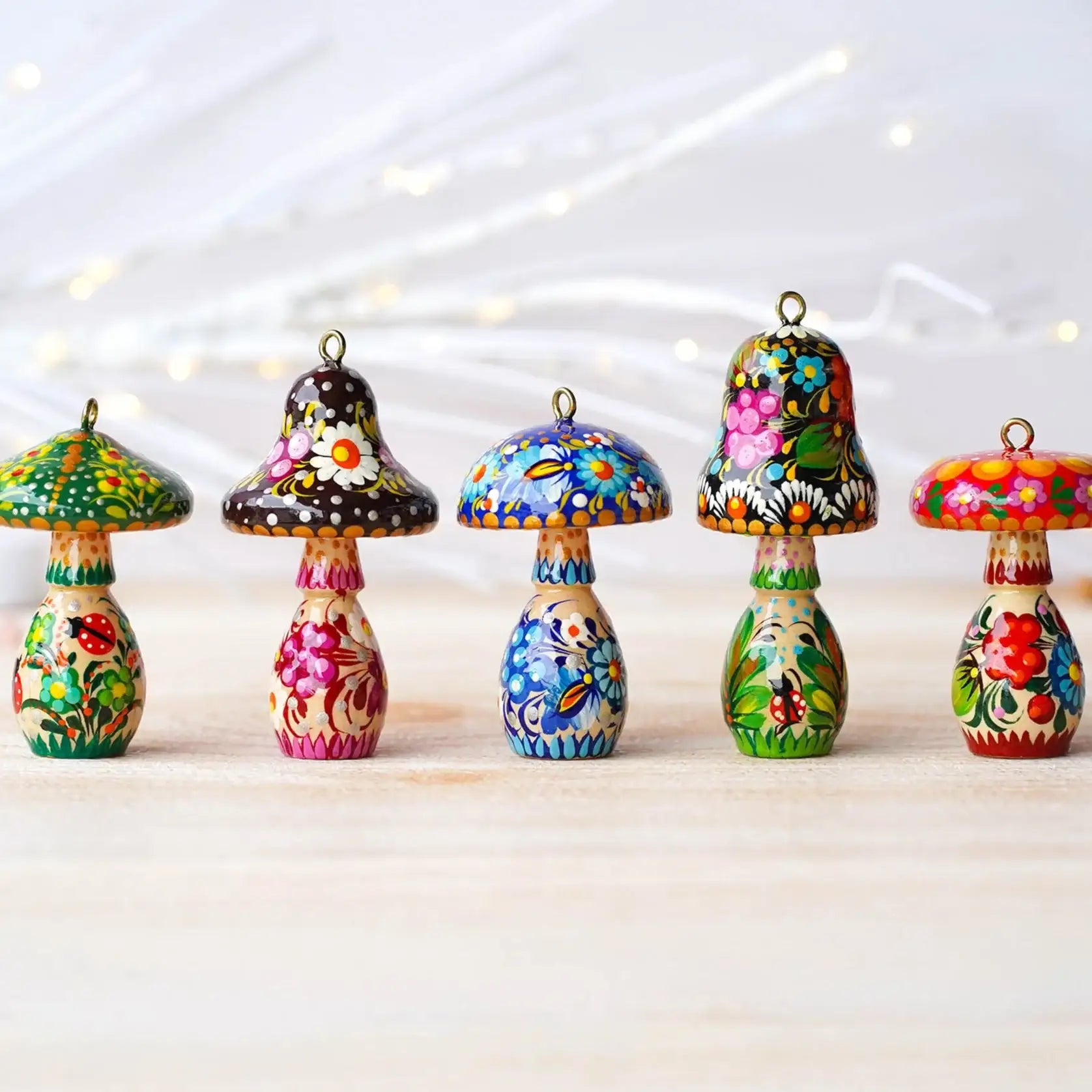 Set of colorful mushroom-shaped ornaments on a light wooden surface with a soft, blurred background.
